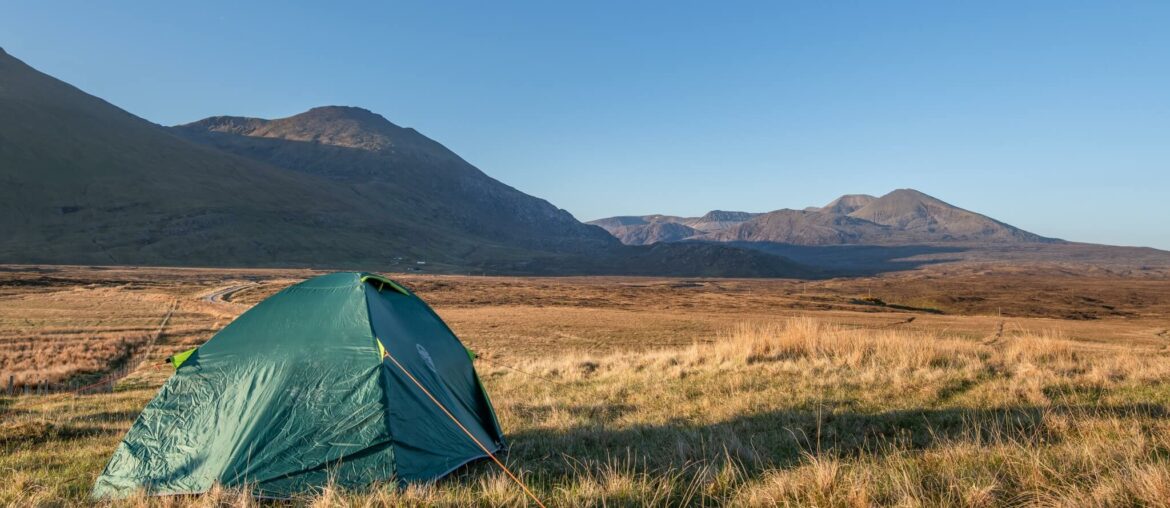 a tent in a field with mountains in the background wild camping