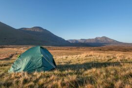 a tent in a field with mountains in the background wild camping