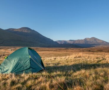 a tent in a field with mountains in the background wild camping