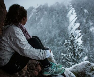 woman sitting on a mountain in winter, choosing womens hiking trousers for summer and winter