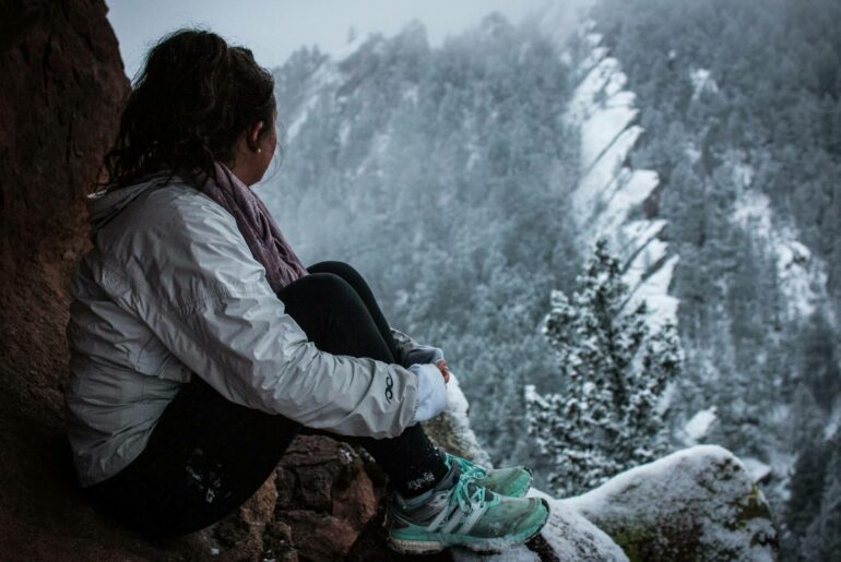 woman sitting on a mountain in winter, choosing womens hiking trousers for summer and winter